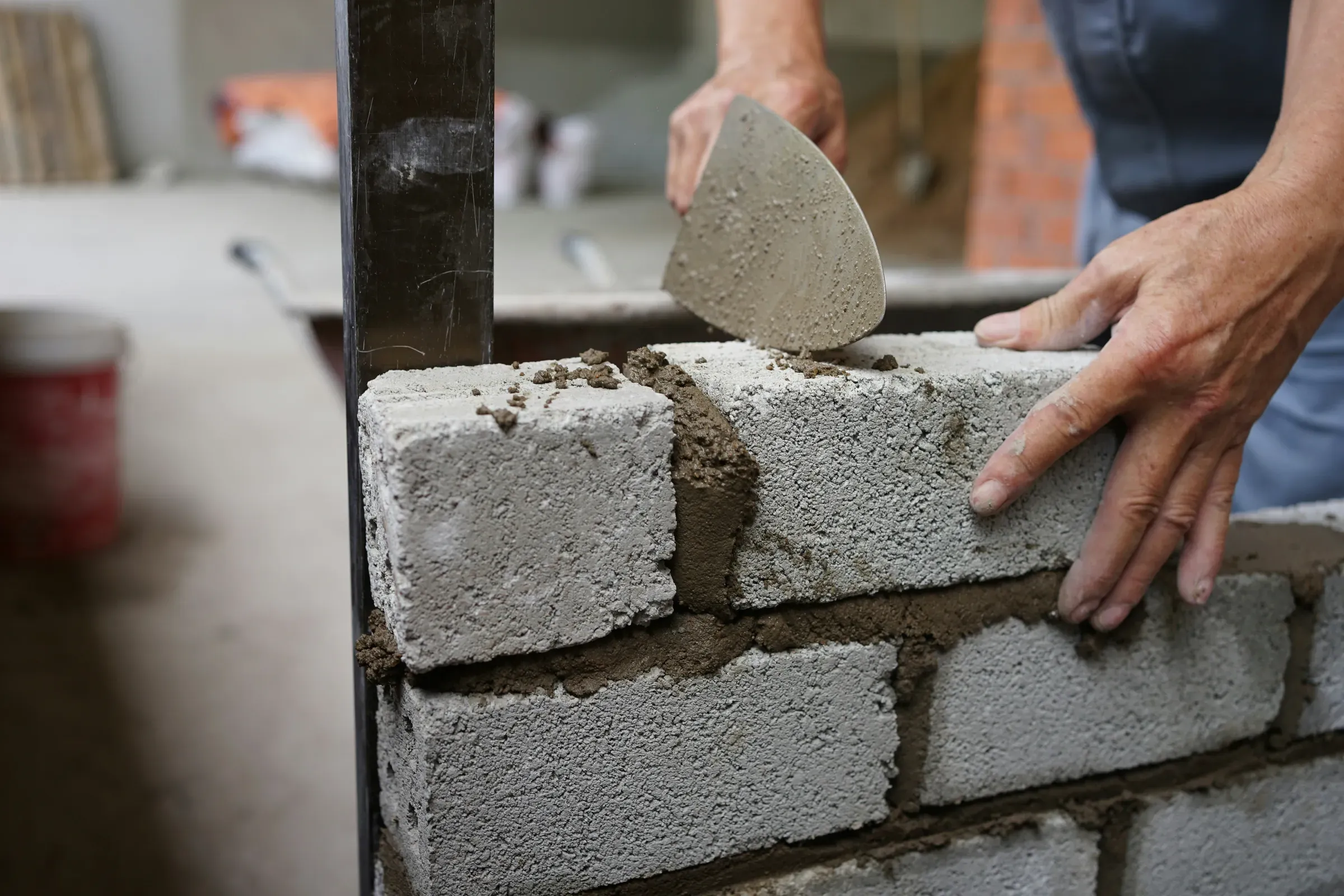 Builder laying concrete blocks with a trowel
